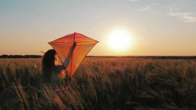 Childhood dream. Happy girl run with a kite in a field of wheat. Pretty girl playing with kite in wheat field on summer day. Happy family. Freedom of action. Childhood, lifestyle concept.