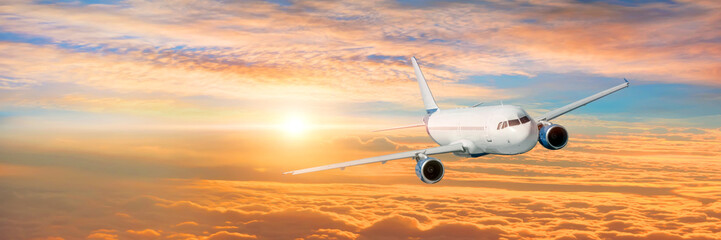 Naklejka na ściany i meble Wide panoramic view, banner of a flying passenger plane on a picturesque sunset sky, travel trip.