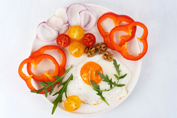 Healthy breakfast in the morning with fried egg and vegetables on white plate. Top view.