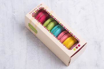 Angle shot of colorful French macarons placed in a cute box with a transparent top. - Powered by Adobe