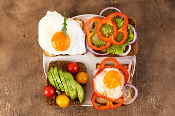 Healthy breakfast with various of sandwiches and toasts on the white plate. Wooden background. Top view.