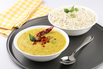 Indian popular food Dal fry or traditional Dal Tadka Curry or yellow lentil curry served with jeera rice in ceramic bowls on bamboo serving tray