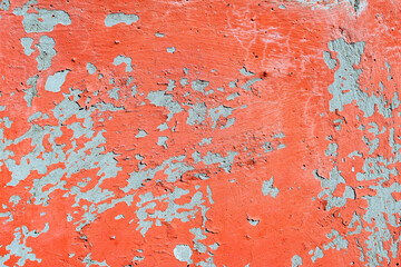 Old orange cracked paint on a concrete wall with a hole
