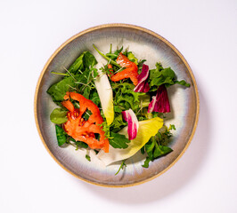 Blattsalat in einer Keramikschüssel mit einen weißen Hintergrund.