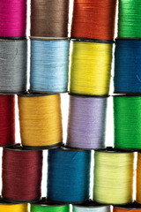 macro close up of colourful cotton bobbins stacked on top of each other to produce a pattern