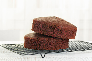 Just baked Chocolate sponge cake on the cooking iron grid, white table. Fluffy, moist and rich chiffon Cake, homemade. - obrazy, fototapety, plakaty