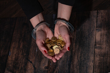 Women's handcuffed hands with a handful of euro coins