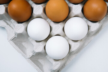 Flat lay of white and brown eggs in egg paper box. Fresh chicken eggs background. Top view natural organic egg. Healthy real food