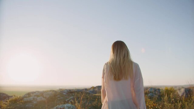 Beautiful blonde woman at sunset goin to the mountains and turning back
