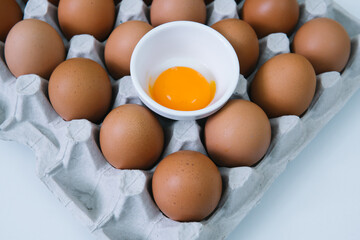 Brown raw chicken eggs and alone broken egg in a tray top view