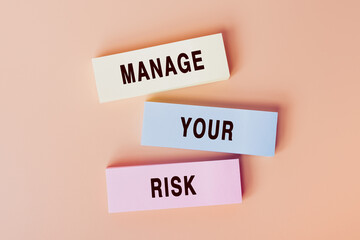 Manage Your Risk. Concept of text on color cards. Top view image of cards and on pastel beige background. Flat lay design