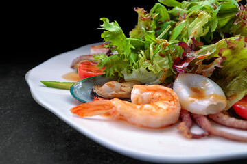 Mix salad with seafood on a dark background