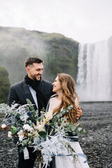 Stylish Bride and groom on elopement near Skogafoss waterfall. Iceland wedding
