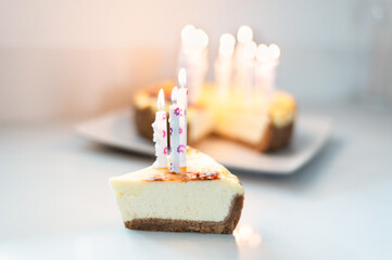 Slice of Classic plain New York Homemade Vanilla Cheesecake with lit candles