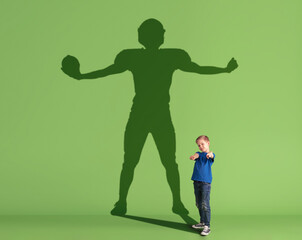 Conceptual image with little kid dreaming about future sport career and shadow of male american...