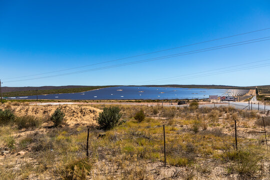 Large solar farm in a remote semi desert area, with paralel rows of photovoltaic panels. no clouds in the sky