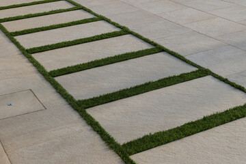 strips of green synthetic grass like real between stone tiles