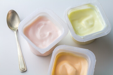 Flavoured yogurt in plastic pots - colourful fruit flavoured yogurt cups isolated on white with...