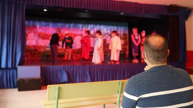 Unrecognizable Drama Teacher Directing A Group Of Unrecognizable Boys And Girls In A Play In The School Theater.