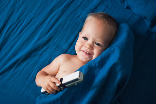 Toddler Boy Plays With Car On Bed Close-up.