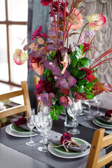 Floral arrangement on the dining table with decor. Family dinner and table setting.