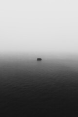 Lonely rock in the middle of the sea with a misty vibe