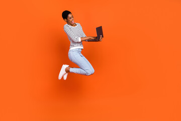 Fototapeta na wymiar Photo of cute charming third gender person wear pullover jumping typing device empty space isolated orange color background