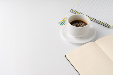 Cup of coffee and notepad on white background