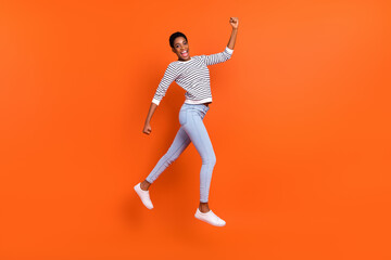 Fototapeta na wymiar Full length body size view of attractive cheerful slim fit girl jumping running isolated over vivid orange color background