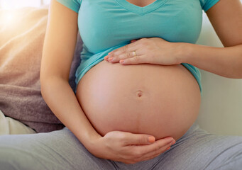 Motherhood is a special journey. Closeup shot of a pregnant woman holding her belly at home.