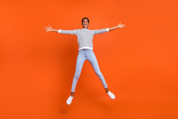 Fototapeta na wymiar Full length body size view of attractive cheerful girl jumping having fun isolated over vivid orange color background