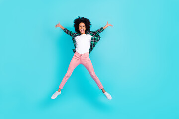 Photo of cheerful crazy active lady jump raise hands have fun wear checkered shirt isolated teal color background