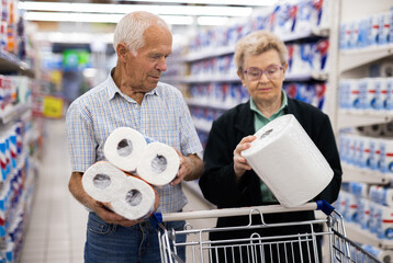 mature couple chooses paper towels in department of supermarket