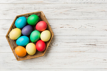 Fototapeta na wymiar Multi colors Easter eggs in the woven basket on colored background . Pastel color Easter eggs. holiday concept with copy space