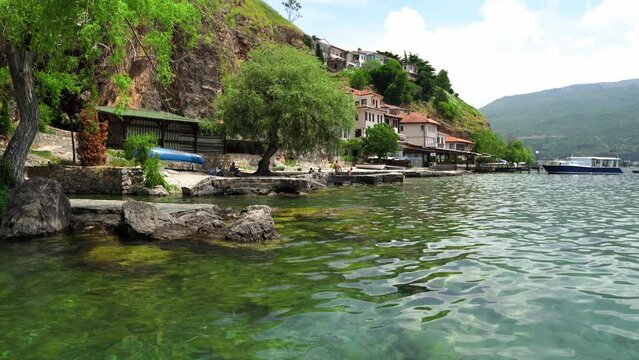 Scenic view from the pier to Ohrid. City of Ohrid in North Macedonia. A city on the eastern shore of Lake Ohrid. Mountain area. City embankment. Boats near the shore. The deepest and oldest lake 