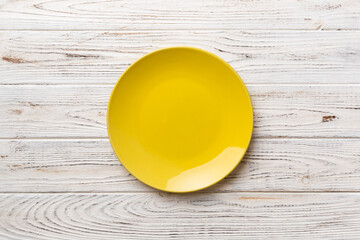 Top view of empty yellow plate on wooden background. Empty space for your design
