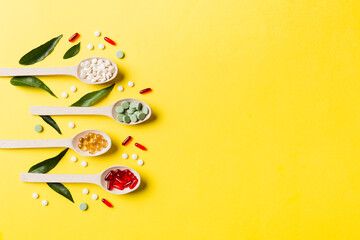 Top view Variety of vitamin and mineral pills in wooden spoon on Colored background. Top view of assorted pharmaceutical medicine pills. Dietary supplement healthcare product