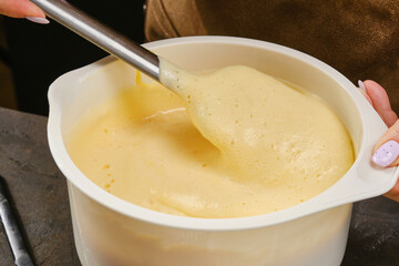 The cook are preparing a culinary product, dough, kneading the dough with a spatula. Shallow depth of field