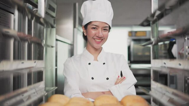 Smiling  asian  female bakers looking at camera..Chefs  baker in a chef dress and hat, cooking together in kitchen.Team of professional cooks in uniform preparing meals   in the kitchen.