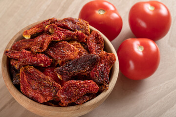 Fresh tomatoes and sun-dried tomatoes on wooden background	