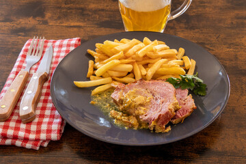 slice of roast pork with mustard on a plate with fries
