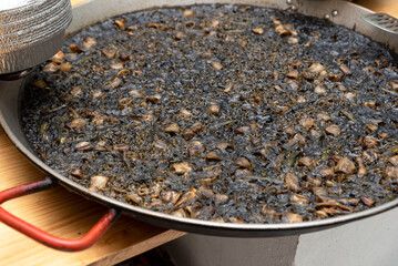arroz negro, black rice, traditional Valencian dish similar to the seafood paella, but cooked with...