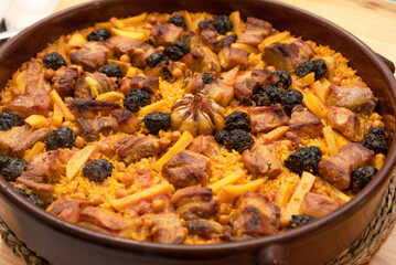Baked rice prepared in a casserole, accompanied by pork, chickpeas, black pudding, tomato and...