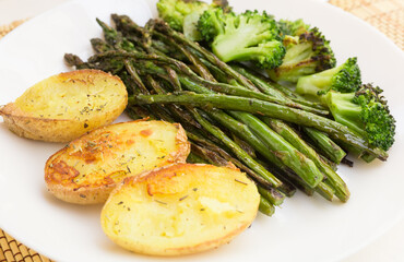 lean dish of cooked fried inflorescences of broccoli, asparagus growth and baked potatoes and Provencal herbs