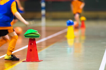 Happy children play indoor sports class. Kids running around training cone during physical...