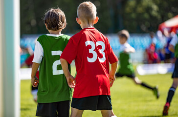 Fototapeta premium Two Young Boys Comptete in Sports Game. Kids in Opposite Team Standing Side By Side in Red and Green Jersey Shirts. School Kids Play Football in Sunny Summer Day