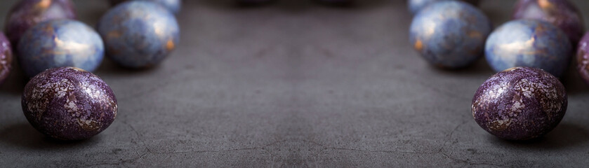 Easter card with a copy of the place for the text. Purple, blue and golden eggs on a dark background. The trend of 2022 purple shade is very peri. Natural dye karkade tea. Top view.