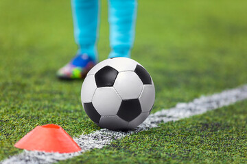 Legs of Footballer Running Towards Soccer Ball on Sideline. Classic Soccer Ball Lying on Pitch Sideline