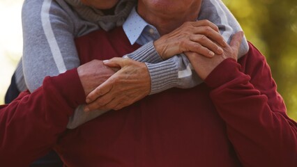 Aged Caucasian married couple hugging and holding their hands focus on hands no faces visible selective focus closeup. High quality photo