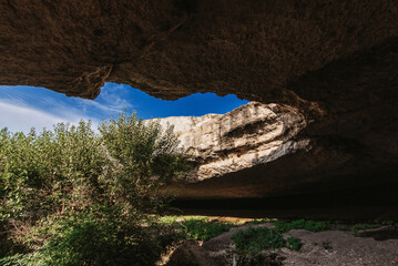 View from a cave in mountains to blue sky on a sunny summer day